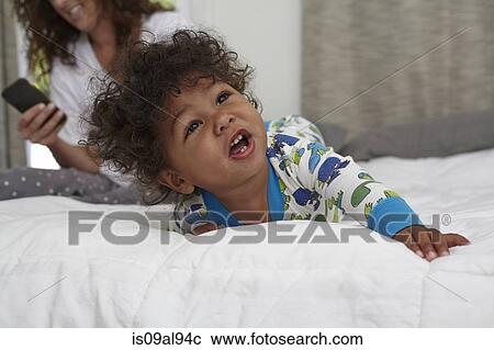 Male toddler crawling on bed whilst mother using smartphone View Large Photo Image Stock Image - Male toddler crawling on bed whilst mother using smartphone. Fotosearch