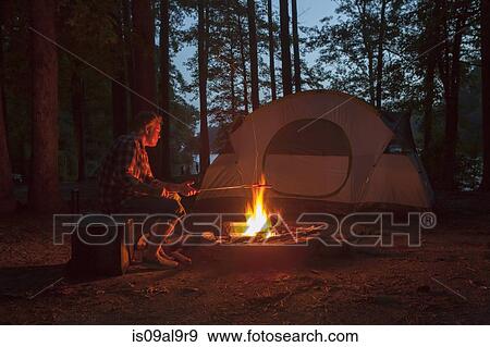 Stock Photo - Man cooking on campfire in forest at night, Arkansas, USA. Fotosearch