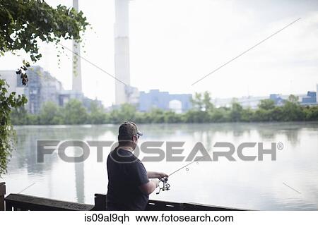 Stock Image - Man fishing opposite Detroit Edison Power Station, river Raisin, Monroe, Michigan, USA. Fotosearch