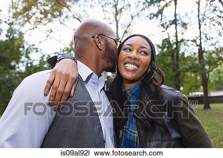 Man kissing woman's cheek in park View Large Photo Image Stock Image - Man kissing woman's cheek in park. Fotosearch