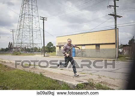 Man running in panic along industrial road, Detroit, Michigan, USA View Large Photo Image Stock Image - Man running in panic along industrial road, Detroit, Michigan, USA. Fotosearch