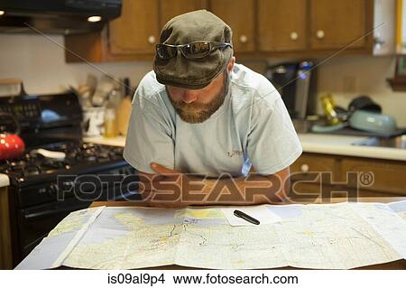 Man studying map of USA at kitchen table View Large Photo Image Picture - Man studying map of USA at kitchen table. Fotosearch