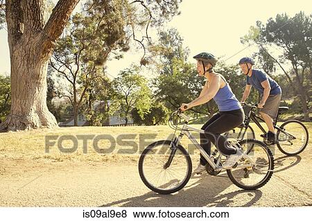 Stock Photo - Mature couple cycling in park. Fotosearch