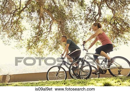 Stock Photograph - Mature couple cycling in park. Fotosearch