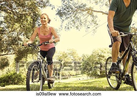 Stock Photo - Mature couple cycling through park. Fotosearch