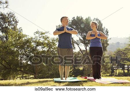 Stock Image - Mature couple practicing yoga in park. Fotosearch