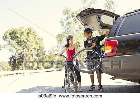 Mature couple removing bicycles from car boot in park View Large Photo Image Stock Image - Mature couple removing bicycles from car boot in park. Fotosearch