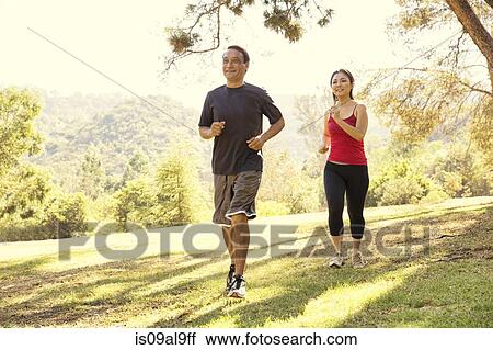 Stock Image - Mature couple running in park. Fotosearch