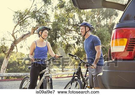 Stock Photo - Mature cyclist couple chatting in park. Fotosearch