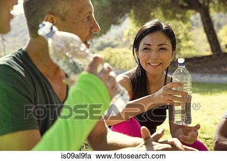 Mature male and female runners taking a water break in park View Large Photo Image Stock Image - Mature male and female runners taking a water break in park. Fotosearch