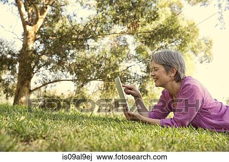 Mature woman using touchscreen on digital tablet in park View Large Photo Image Stock Image - Mature woman using touchscreen on digital tablet in park. Fotosearch