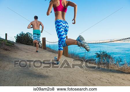 Mid adult man and young giving running on path by sea, rear view View Large Photo Image Stock Photo - Mid adult man and young giving running on path by sea, rear view. Fotosearch