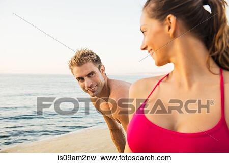 Mid adult man and young woman on beach, looking at each other View Large Photo Image Stock Photo - Mid adult man and young woman on beach, looking at each other. Fotosearch