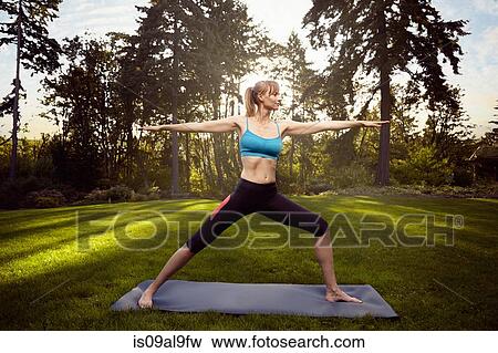 Mid adult woman practicing warrior pose in park View Large Photo Image Stock Photo - Mid adult woman practicing warrior pose in park. Fotosearch