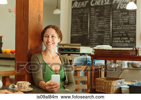 Mid adult woman with smartphone in country store cafe View Large Photo Image Picture - Mid adult woman with smartphone in country store cafe. Fotosearch