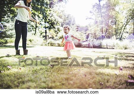 Mother and daughter playing bubbles in garden View Large Photo Image Stock Image - Mother and daughter playing bubbles in garden. Fotosearch