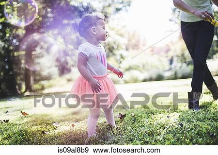 Stock Photo - Mother and daughter playing bubbles in garden. Fotosearch