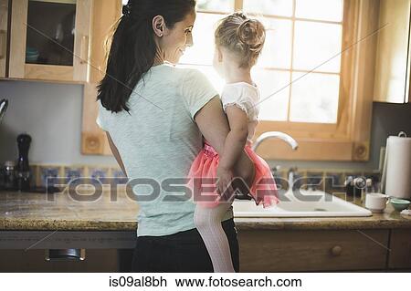 Stock Image - Mother and daughter playing in kitchen. Fotosearch