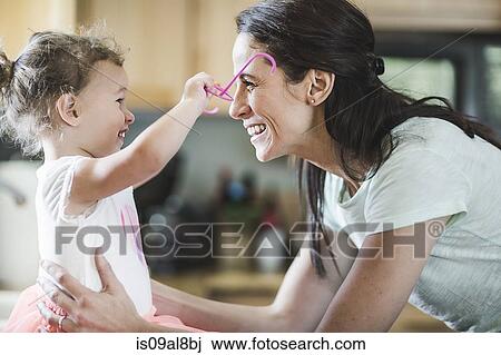 Stock Image - Mother and daughter playing in kitchen. Fotosearch