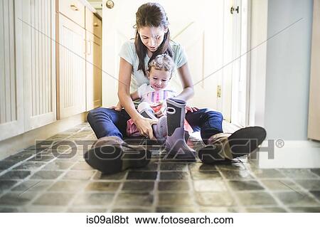 Mother and daughter putting on boots in kitchen View Large Photo Image Stock Photograph - Mother and daughter putting on boots in kitchen. Fotosearch