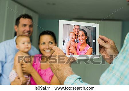 Over shoulder portrait of mid adult couple and baby daughter taken on digital tablet View Large Photo Image Stock Image - Over shoulder portrait of mid adult couple and baby daughter taken on digital tablet. Fotosearch