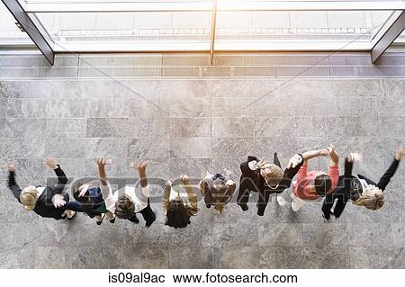 Stock Image - Overhead view of business team in a row jumping for joy. Fotosearch