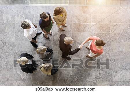 Stock Image - Overhead view of business team meeting client in office. Fotosearch