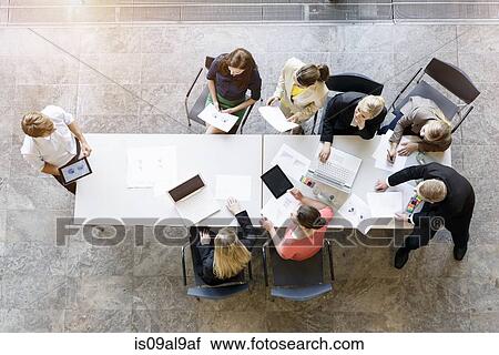 Overhead view of business team meeting at desk in office View Large Photo Image Stock Image - Overhead view of business team meeting at desk in office. Fotosearch