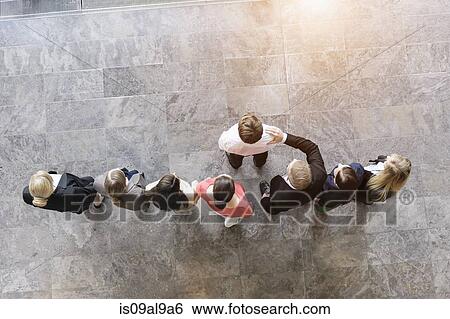 Overhead view of business team congratulating colleague View Large Photo Image Stock Photograph - Overhead view of business team congratulating colleague. Fotosearch