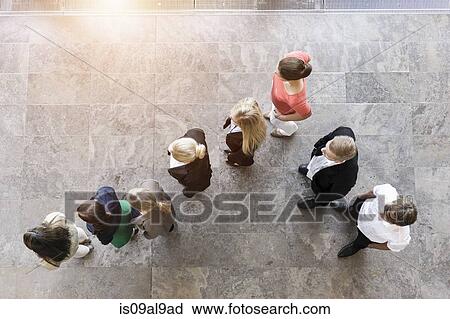 Stock Image - Overhead view of business team watching and listening in office. Fotosearch