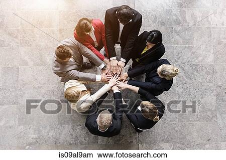 Picture - Overhead view of businessmen and women in circle with hands together. Fotosearch