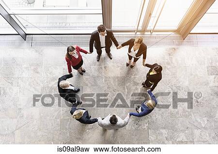 Overhead view of businessmen and women in circle holding hands View Large Photo Image Stock Photo - Overhead view of businessmen and women in circle holding hands. Fotosearch
