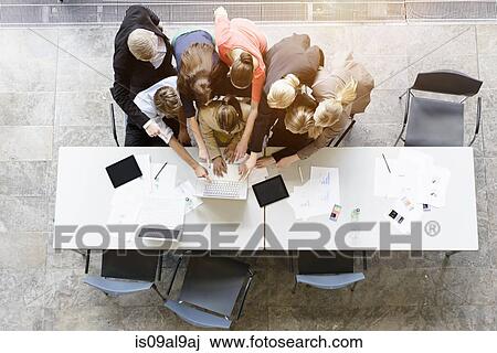 Overhead view of huddled business team brainstorming at desk in office View Large Photo Image Stock Image - Overhead view of huddled business team brainstorming at desk in office. Fotosearch