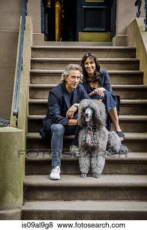 Portrait of mature couple and their poodle sitting on apartment stairway View Large Photo Image Stock Photo - Portrait of mature couple and their poodle sitting on apartment stairway. Fotosearch