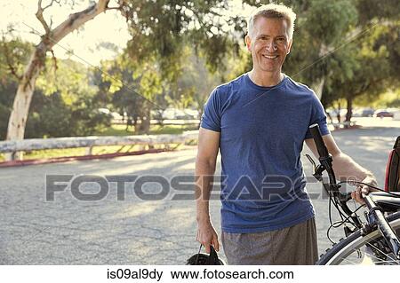 Portrait of mature male cyclist in park View Large Photo Image Stock Photo - Portrait of mature male cyclist in park. Fotosearch