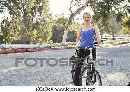 Portrait of mature woman cyclist in park View Large Photo Image Picture - Portrait of mature woman cyclist in park. Fotosearch