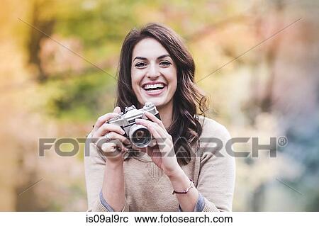 Portrait of smiling young woman using SLR camera in autumn forest View Large Photo Image Stock Image - Portrait of smiling young woman using SLR camera in autumn forest. Fotosearch
