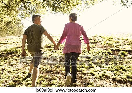 Rear view of mature couple power walking in park View Large Photo Image Stock Image - Rear view of mature couple power walking in park. Fotosearch