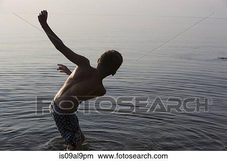 Picture - Teenage boy losing balance in Lake Superior, Au Train Bay, Michigan, USA. Fotosearch