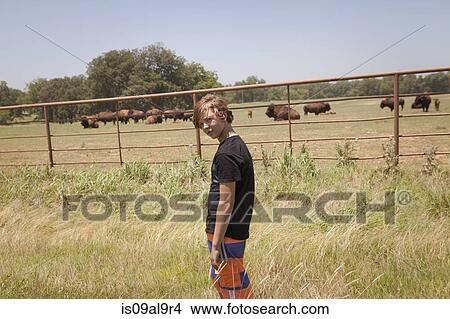 Teenage boy next to buffalo herd in field, Oklahoma, USA View Large Photo Image Picture - Teenage boy next to buffalo herd in field, Oklahoma, USA. Fotosearch
