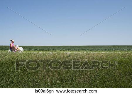 Teenage girl riding tricycle through field View Large Photo Image Picture - Teenage girl riding tricycle through field. Fotosearch