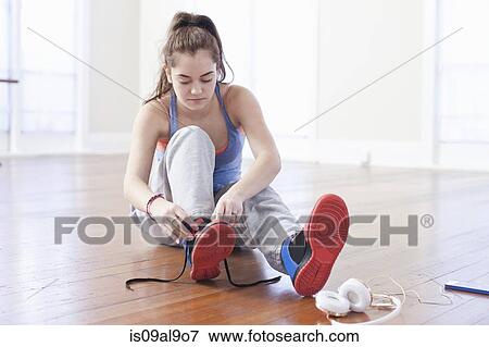 Stock Photo - Teenage girl tying trainer laces in ballet school. Fotosearch