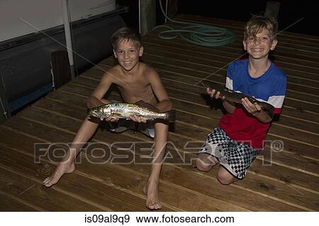 Two brothers on pier at night holding spanish mackerel fish, Shalimar, Florida, USA View Large Photo Image Stock Photo - Two brothers on pier at night holding spanish mackerel fish, Shalimar, Florida, USA. Fotosearch