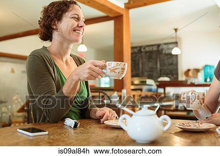 Stock Image - Two mid adult female friends chatting in country store cafe. Fotosearch