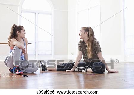 Stock Photograph - Two teenage girls sitting on floor chatting in ballet school. Fotosearch