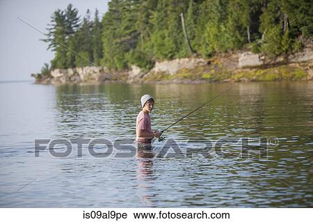 Stock Image - Wading teenage boy fishing in Lake Superior, Au Train Bay, Michigan, USA. Fotosearch