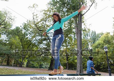 Woman balancing on railing in park View Large Photo Image Picture - Woman balancing on railing in park. Fotosearch