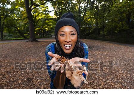 Stock Photograph - Woman blowing autumn leaves. Fotosearch