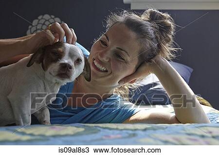 Woman lying on bed petting dog View Large Photo Image Stock Image - Woman lying on bed petting dog. Fotosearch