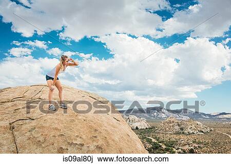 Stock Image - Woman taking break on mountain, Joshua Tree National Park, California, US. Fotosearch